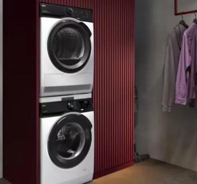 Stacked AEG washing machine and heat pump dryer in a burgundy utility room