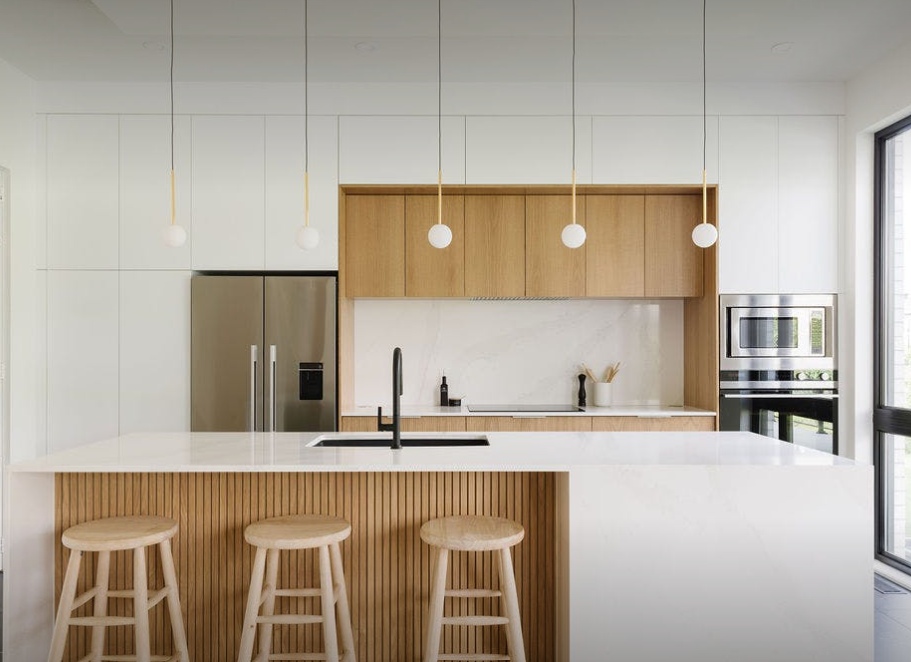 White Silestone worktop and island in a bright handleless kitchen with oak wall units
