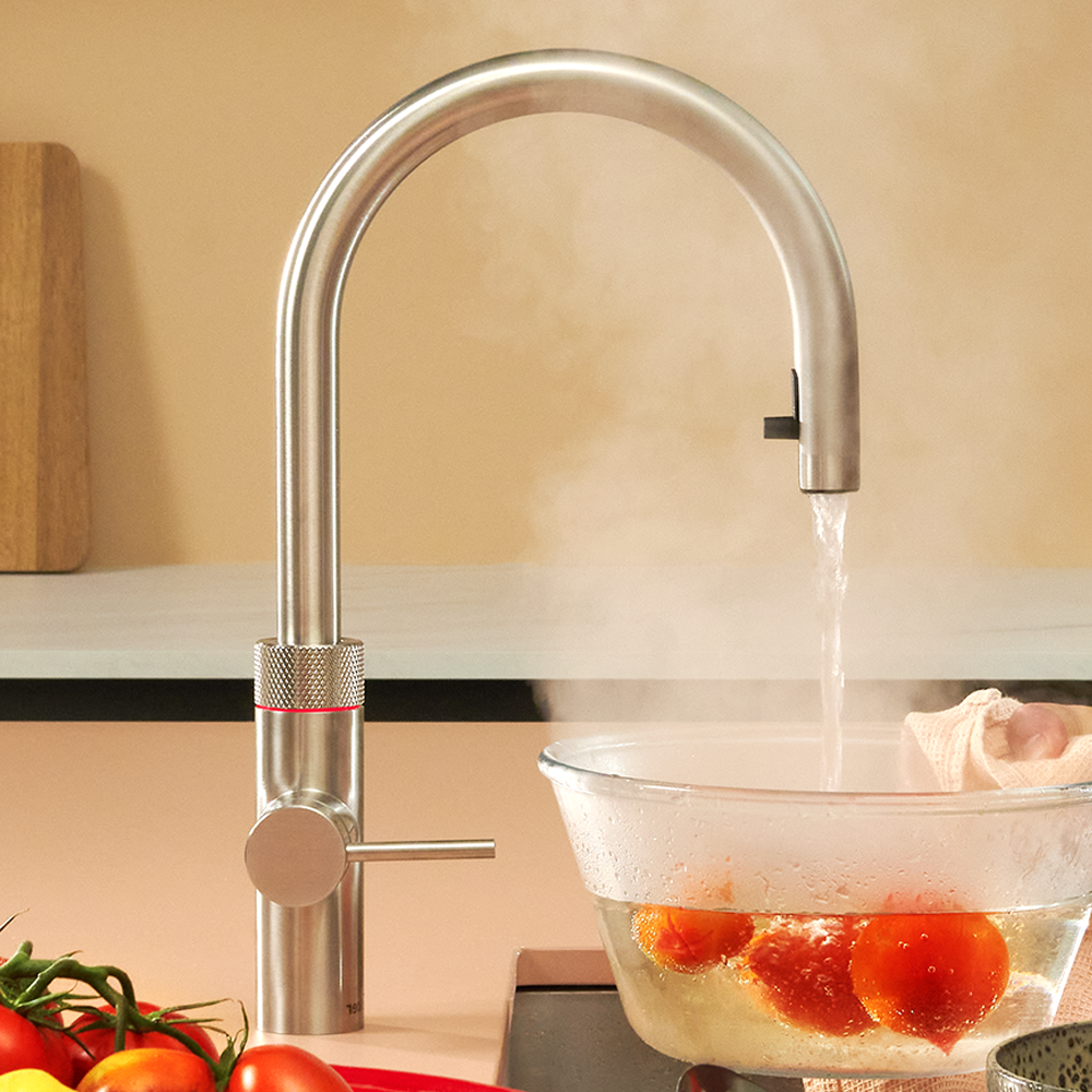 Brushed steel Quooker boiling water tap pouring steaming water into a glass bowl